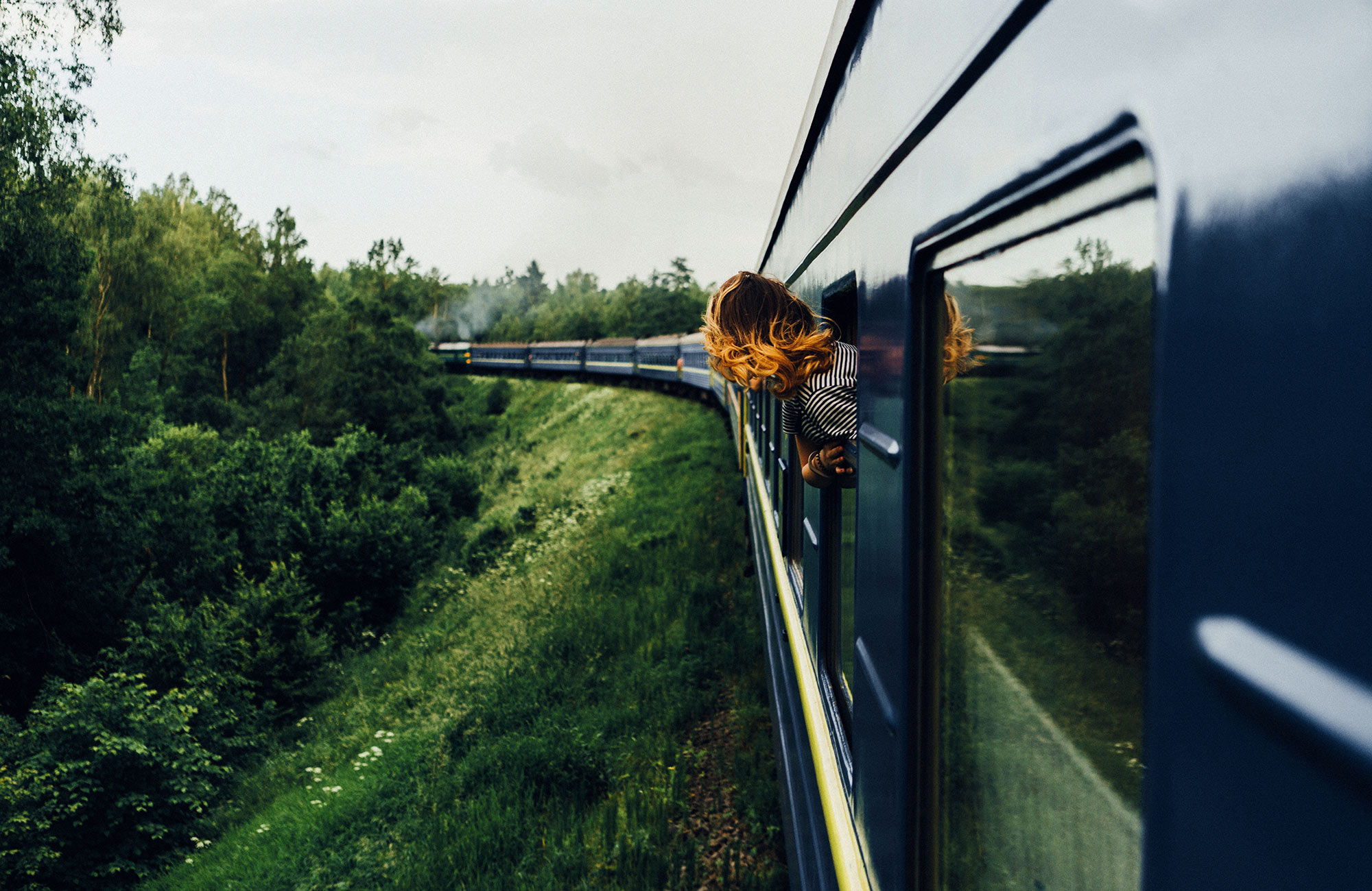 Reiziger hangt uit het raam | Reizen met de trein | KILROY
