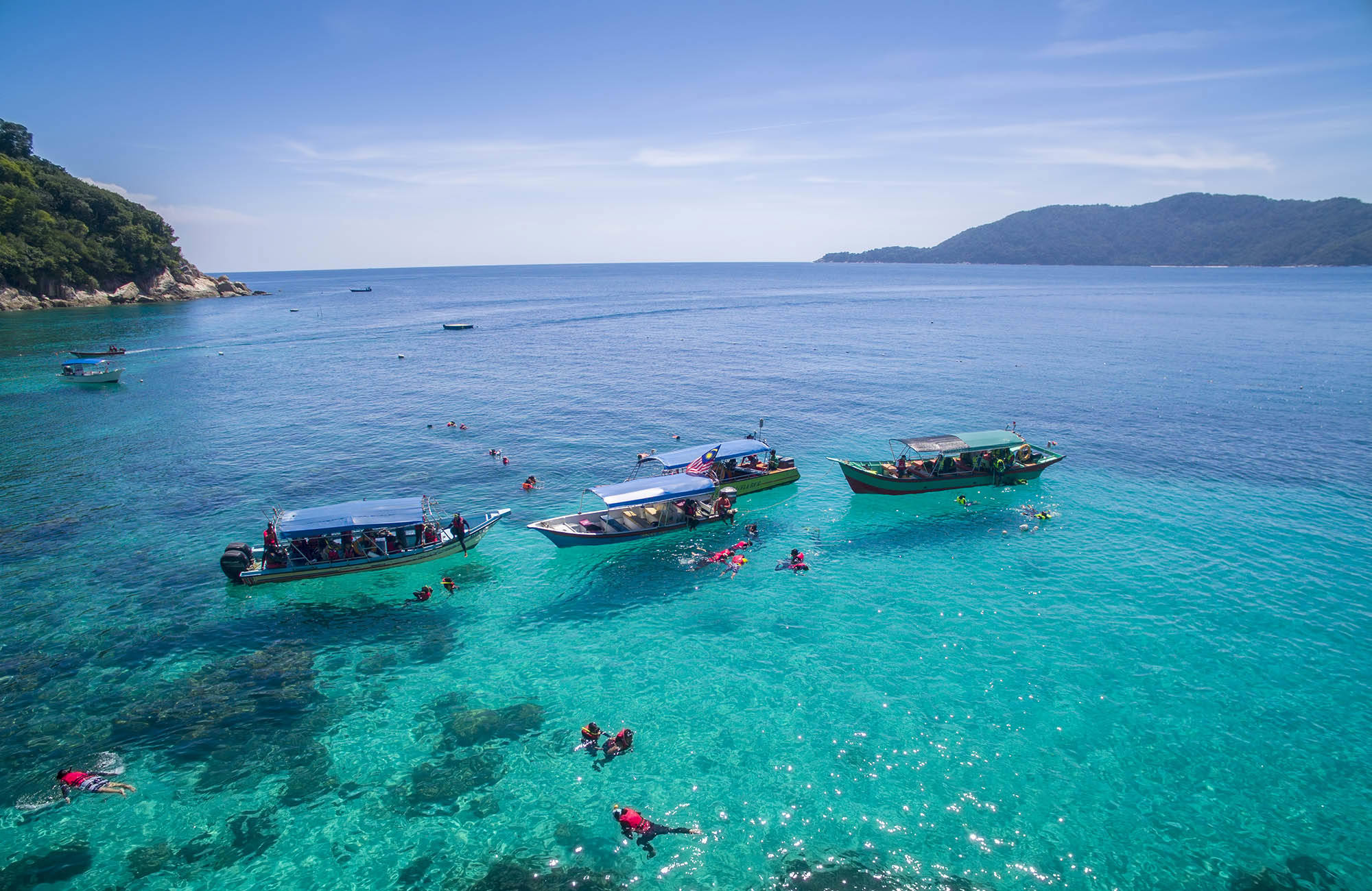 Bootjes en snorkelaars in het water van Perhentian Islands | Beste reistijd augustus | Beste bestemmingen augustus | Reiskalender | KILROY