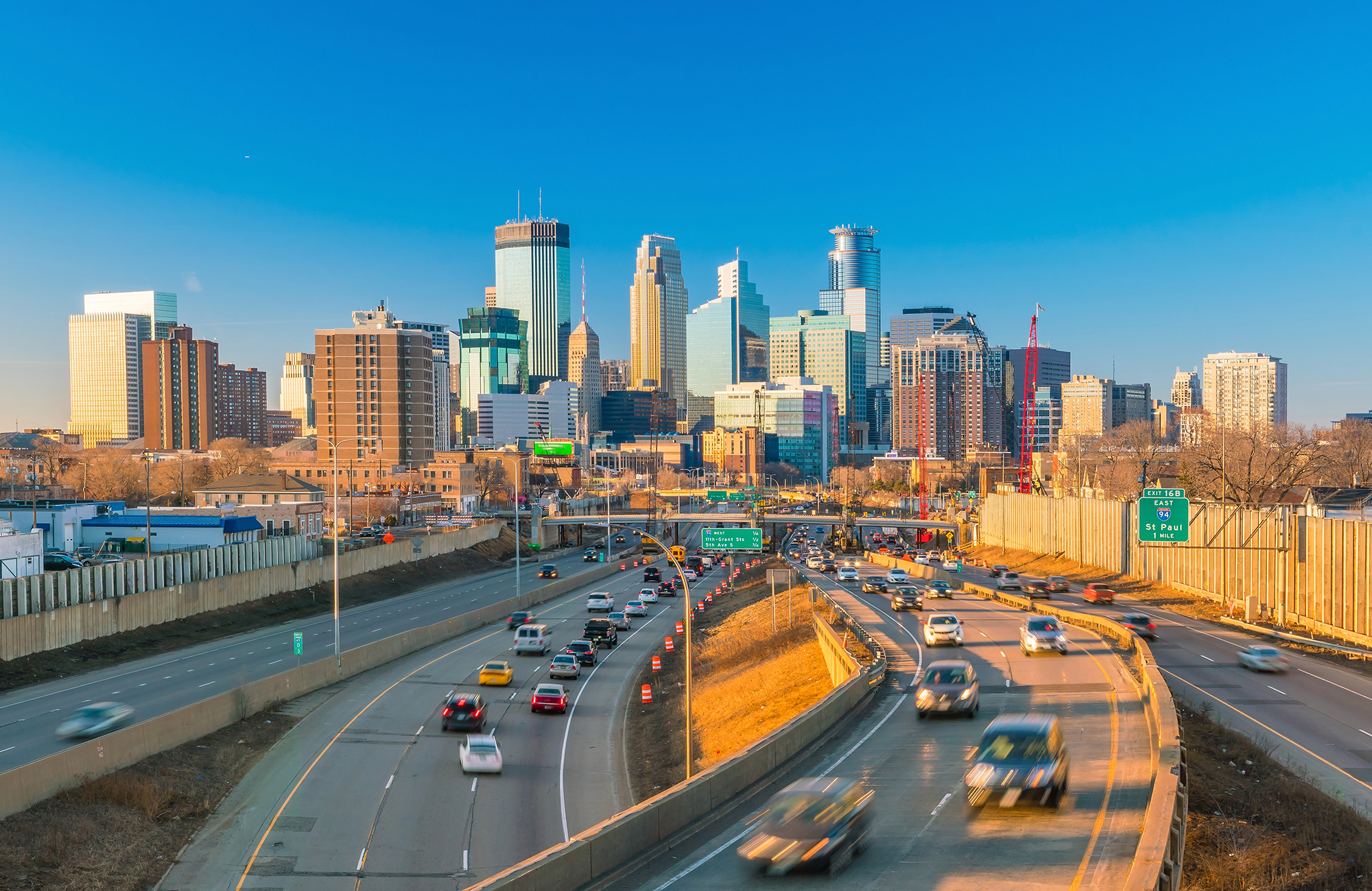 Drukke snelwegen naar Minneapolis, met de skyline van de stad tegen een felblauwe lucht