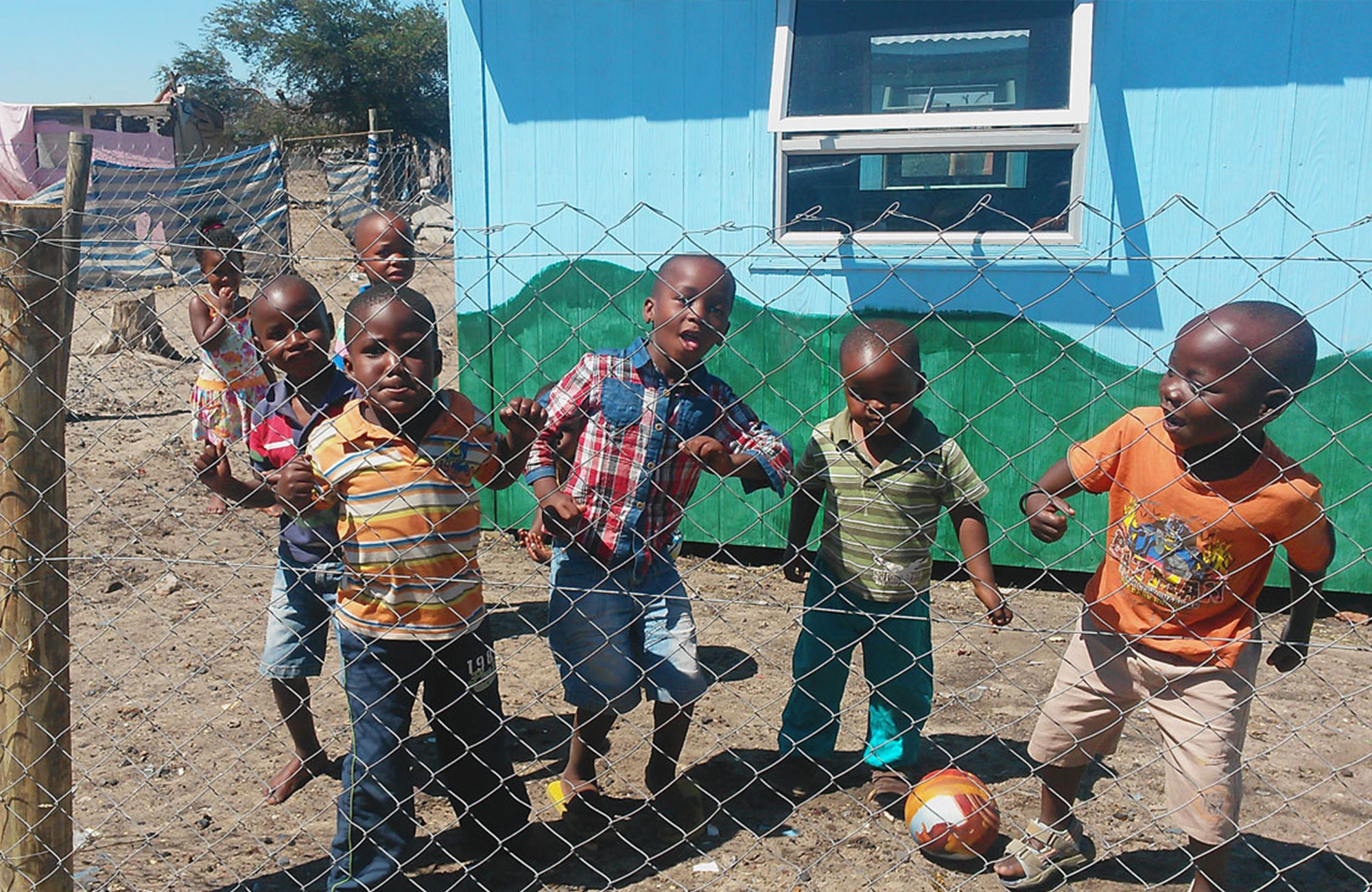 Ett grupp med småpojkar leker på skolgården utanför skolan hos Sunshine Educare
