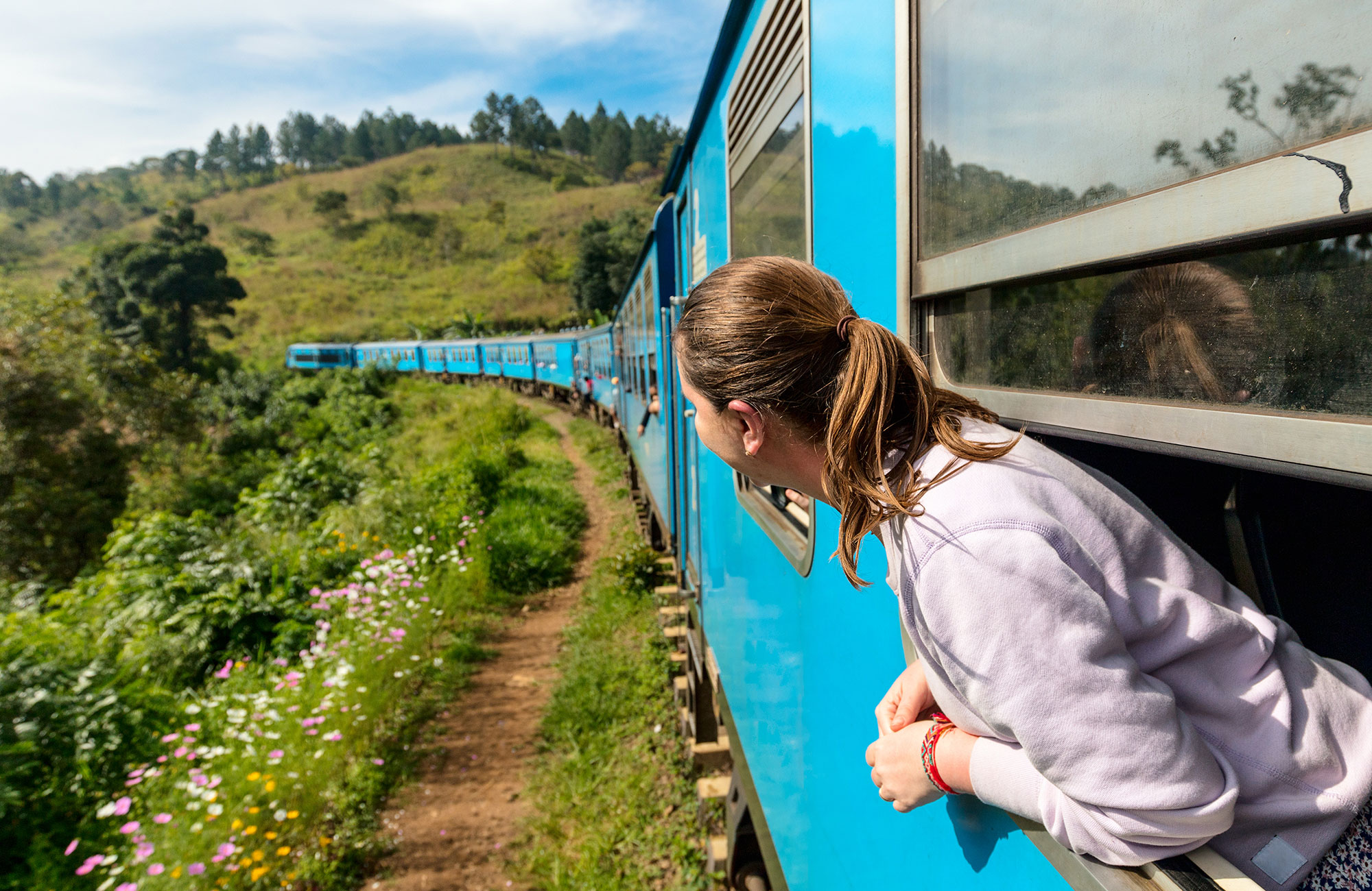 Reiziger hang uit raam van de trein in Sri Lanka | Treinreizen in Azië | KILROY