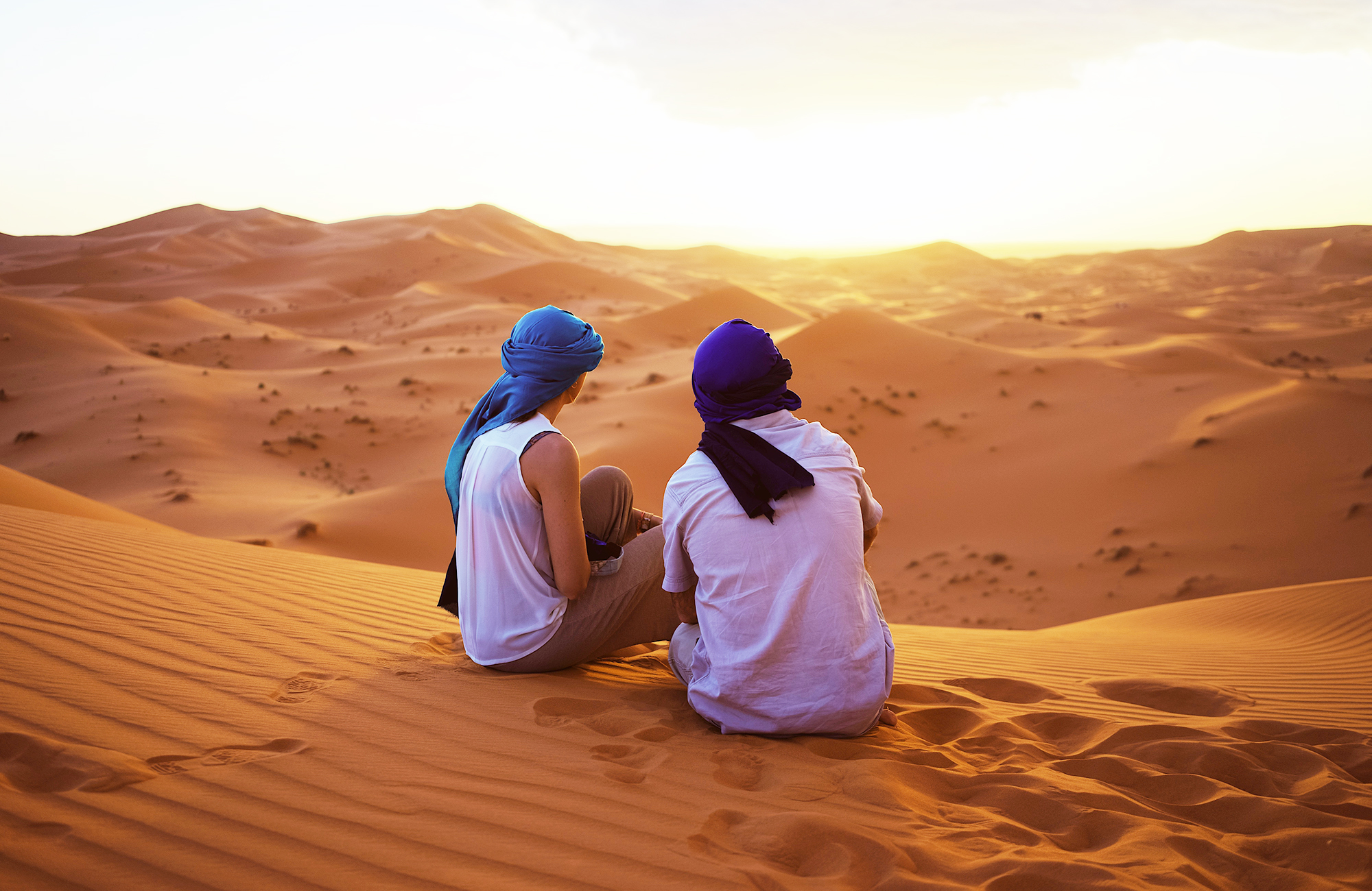 Image of a couple sitting on a sand dune in the Sahara in Morocco - KILROY