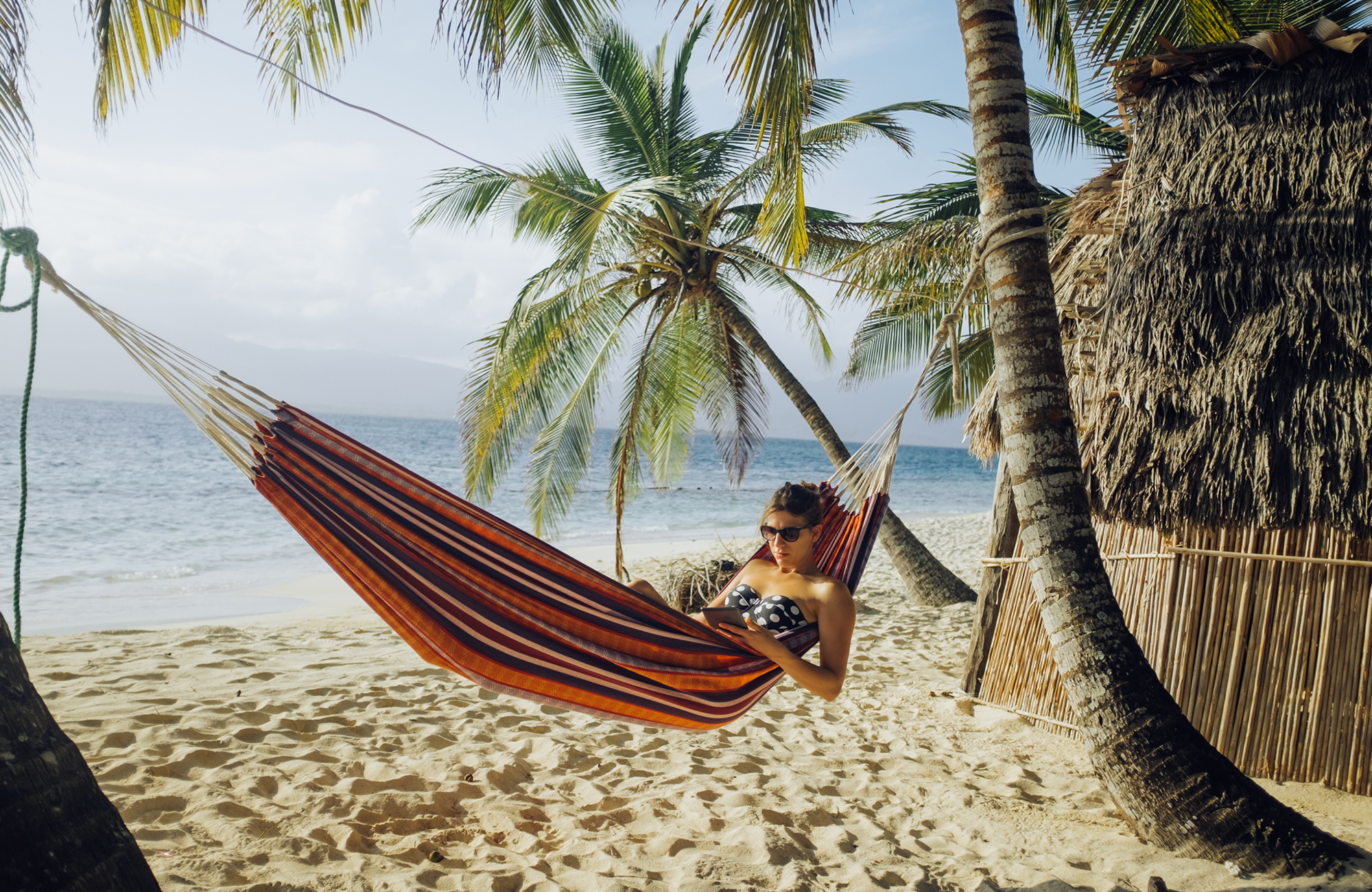 meisje in een hangmat op een strand met palmbomen