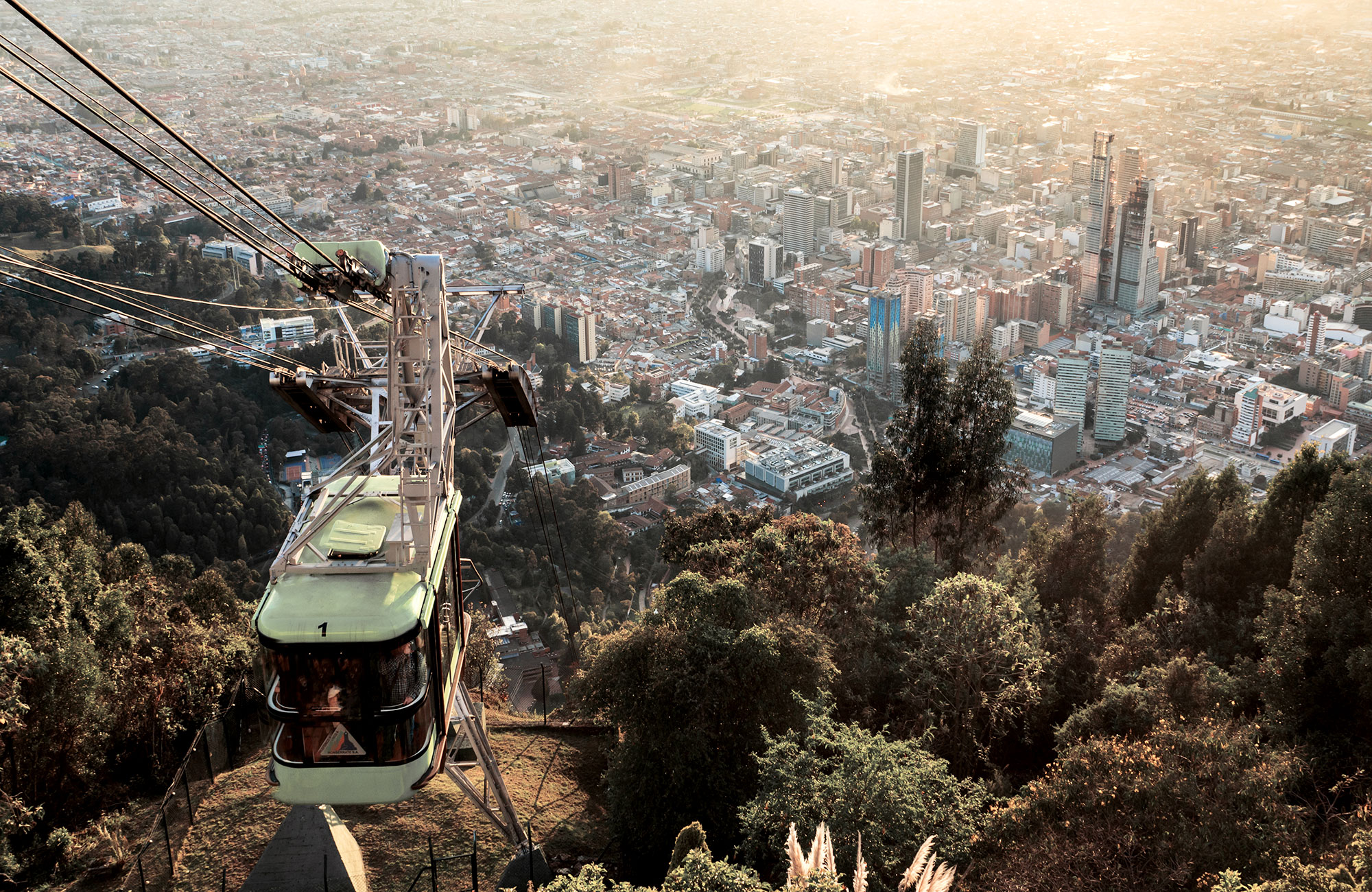 A green cable car going down a hill in the city of Bogota in Colombia