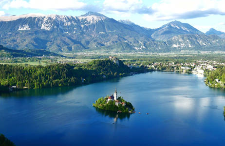 Luchtfoto van eiland in Lake Bled met bergen in de verte | Reizen naar Bled | KILROY