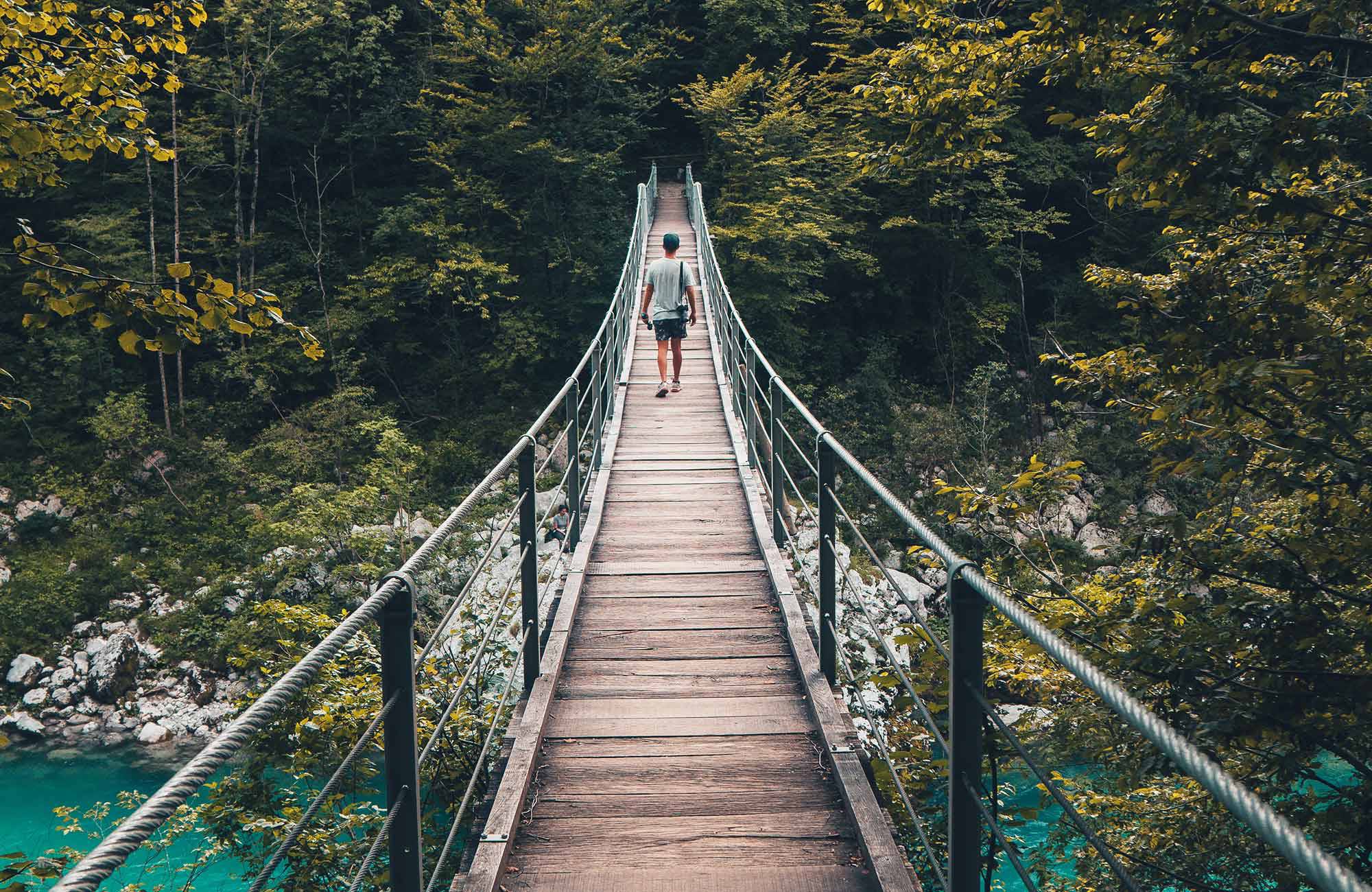 Reiziger loopt over brug in Kamp Lazar in Kobaird, Slovenië | Roadtrip Slovenië | KILROY