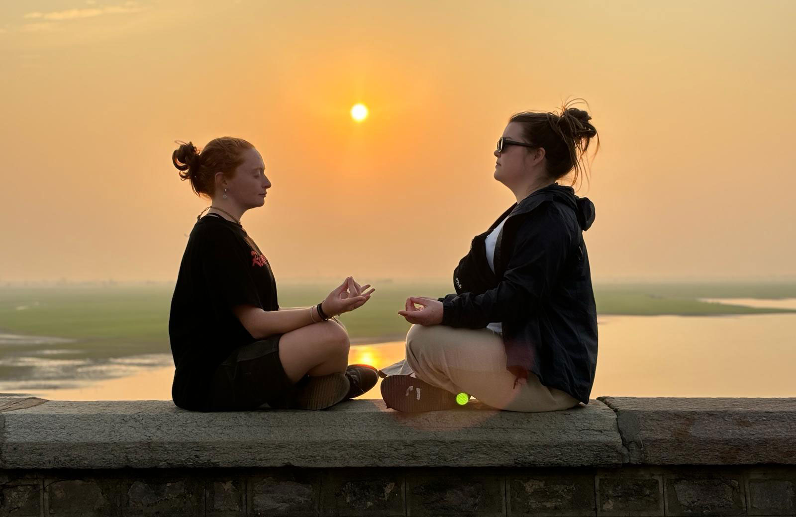 Two girls holding a yoga pose at a lookout point in India - KILROY 