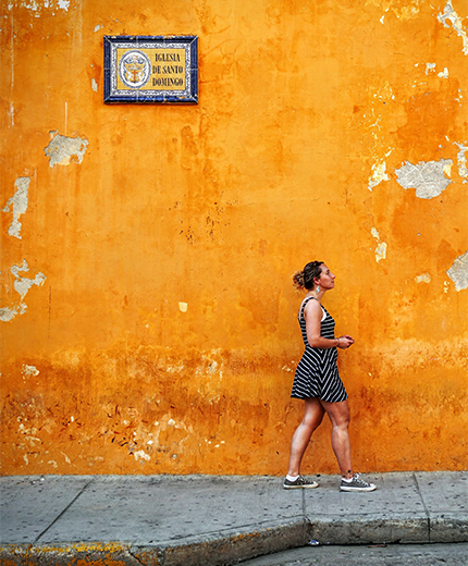 Vrouw voor een oranje muur in Cartagena | Reizen naar Colombia | KILROY