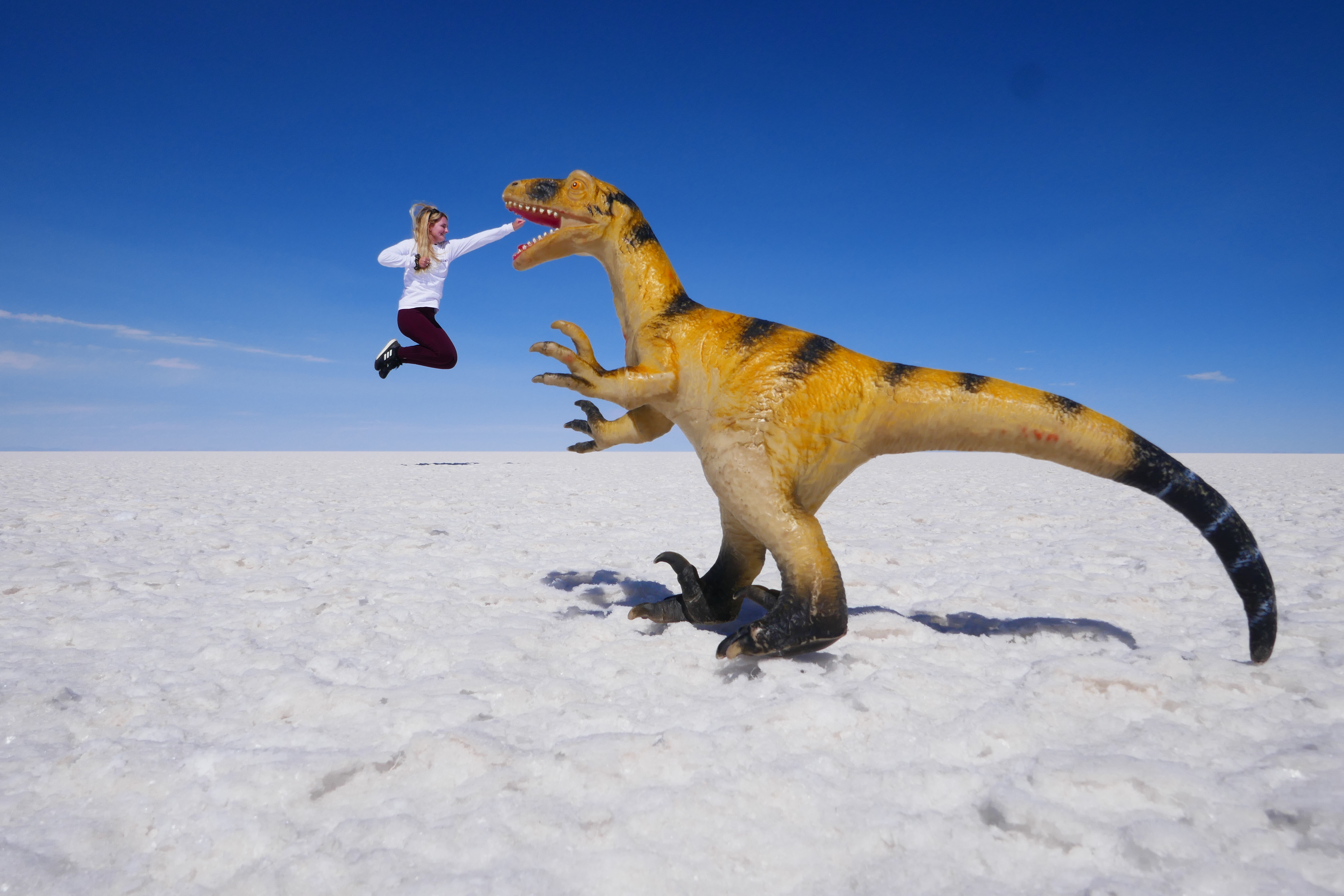 Reizigster met speelgoed dino op de zoutvlakte vanBolivia - KILROY