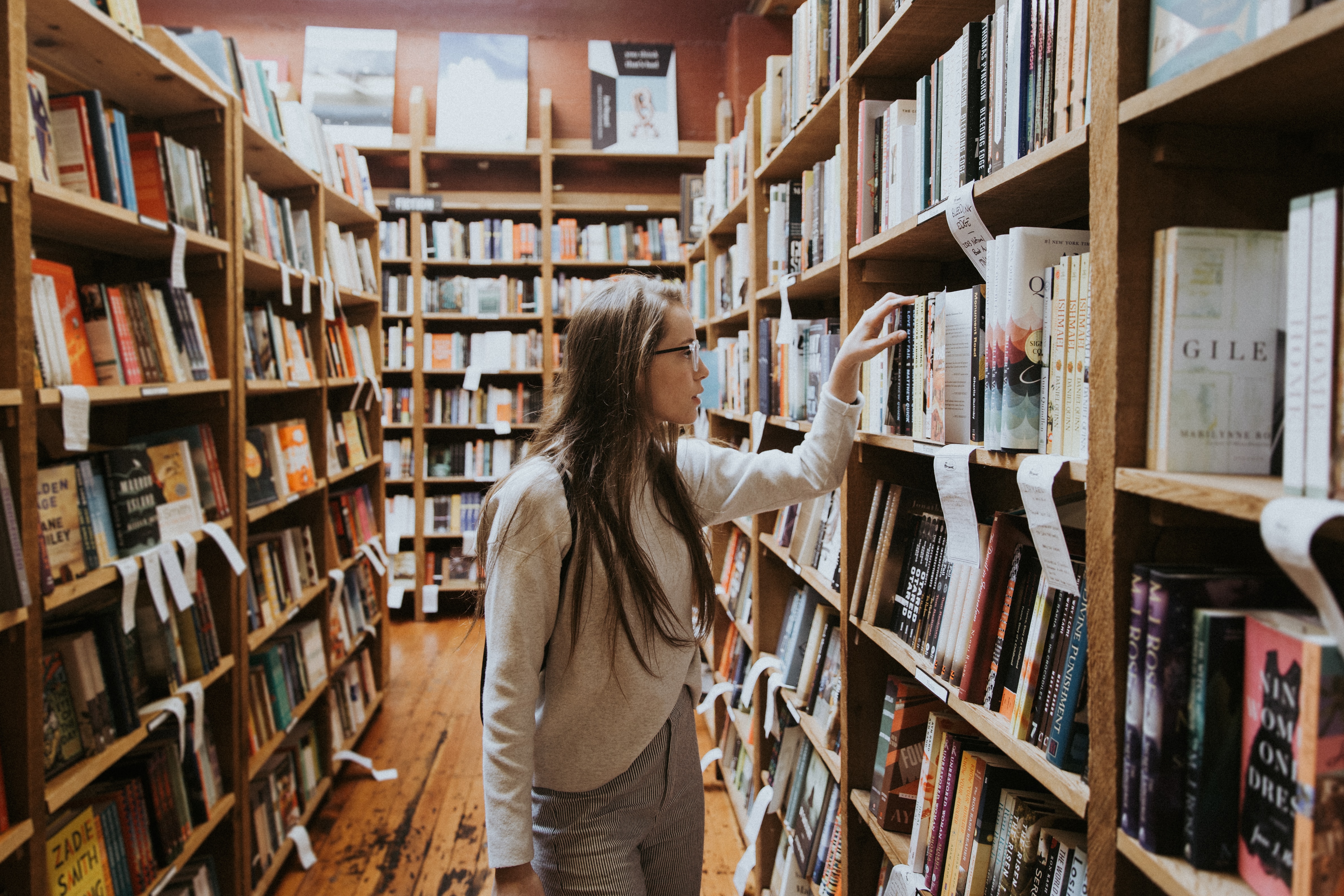 Young woman looking at books in a library | KILROY