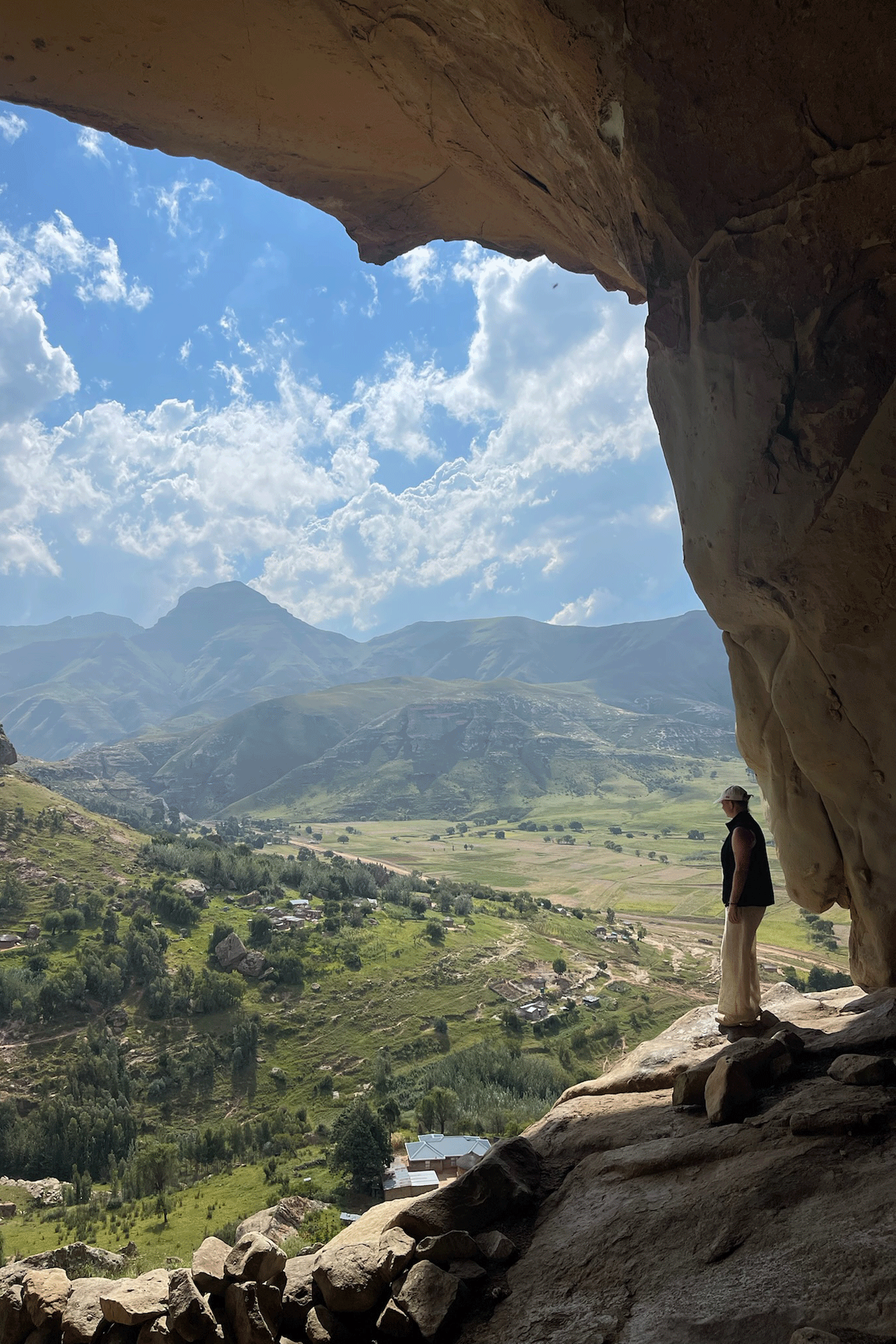 Vrouw op een rots die kijkt naar de groene bergen in Lesotho, Zuid-Afrika