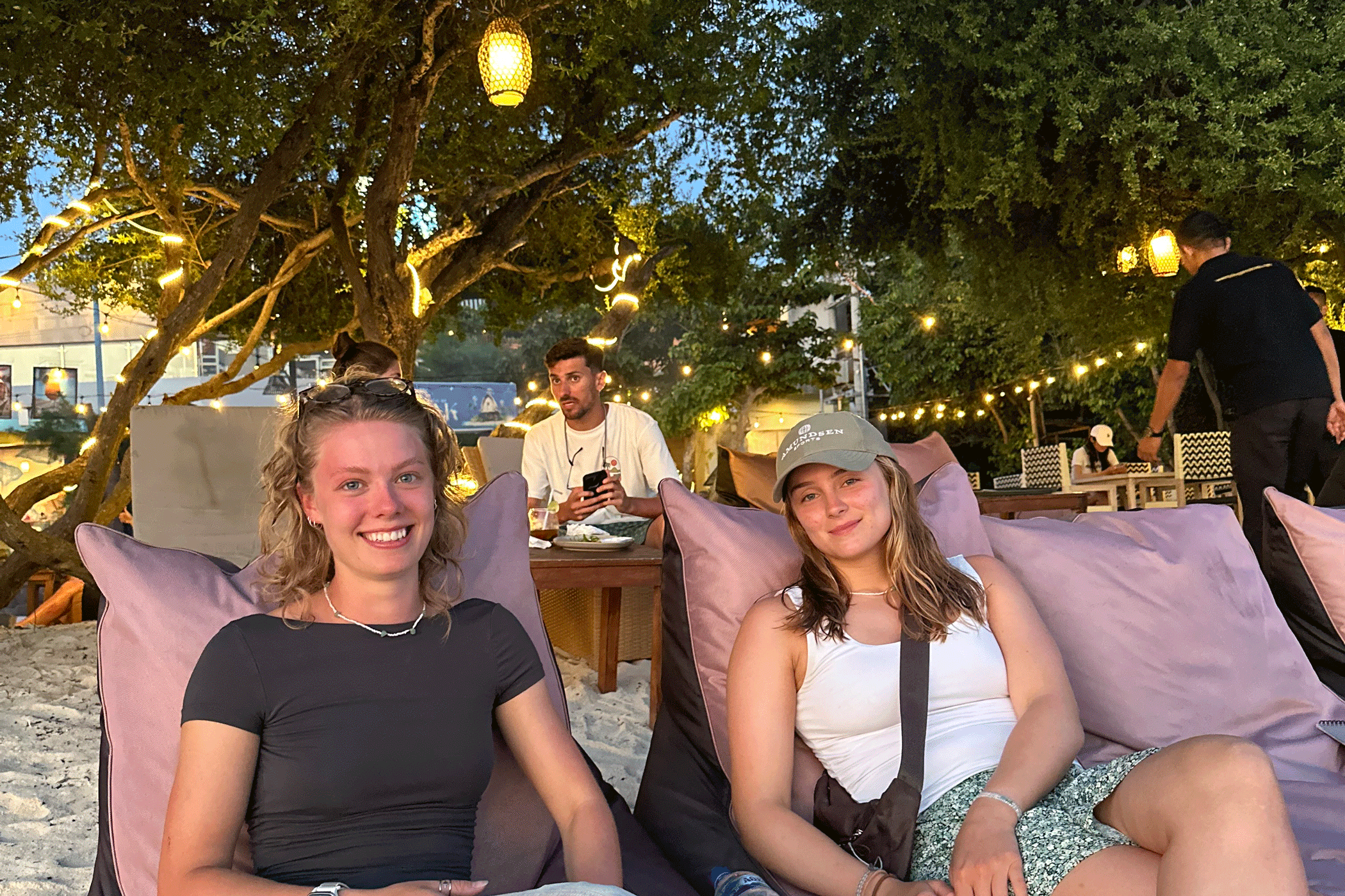 Twee meisjes die glimlachend in zitzakken op het strand van Indonesië zitten